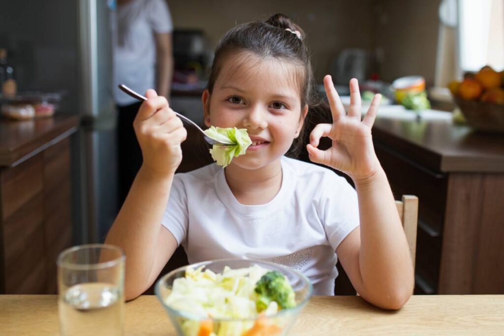 Niña sonriendo con comida saludable / Foto: Freepik