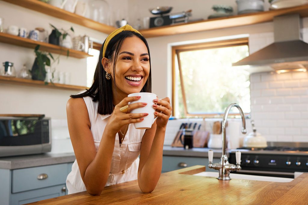 Una mujer sonriente saborea el placer de un buen café, capturando el momento de alegría que esta bebida trae a nuestro día a día. / Foto: Freepik