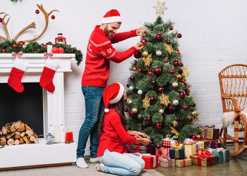 Una pareja unida por la tradición, compartiendo un momento de alegría y festividad mientras decora su árbol de Navidad. / Foto: Freepik